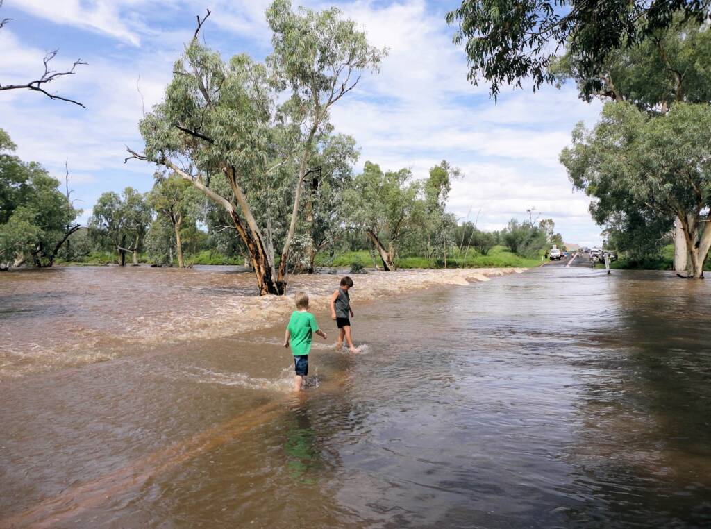 Locals walking through water flowing over Larapinta Drive, Alice Springs, 19 Mar 2011